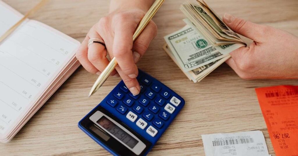 Person calculating expenses with calculator and cash for budgeting planning
