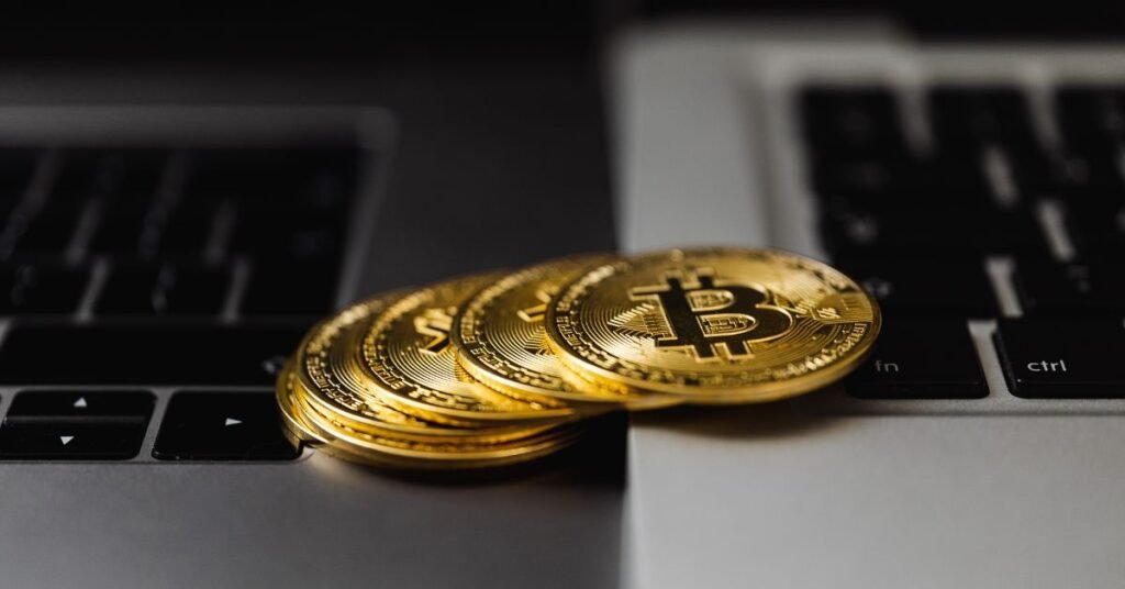 Gold cryptocurrency coins (Bitcoin) placed on a laptop keyboard representing digital currency and online financial trading.