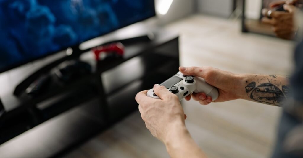 Person playing video game with a controller in front of a TV screen.